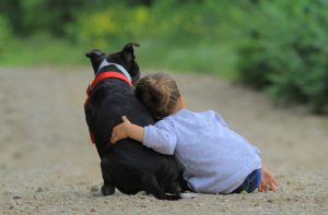 child hugging black dog