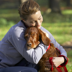 Woman crouching down, hugging dog