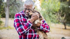older man hugging dog